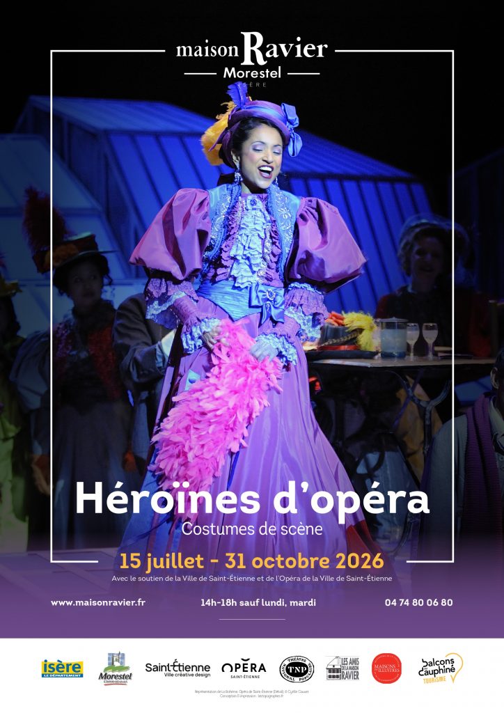 Affiche pour l'exposition "Héroïnes d'Opéra, Costumes de scène", présentée entre le 15 juillet et le 31 octobre 2026 à la Maison Ravier. Les couleurs dominantes sont le bleu et le violet. 
Au premier plan, centrée, on voit une personne portant une longue robe violette aux manches bouffantes, dont les noeuds et autres froufrous sont bleus ciels. Elle porte également un chapeau assorti à sa robe. Derrière, deux autres personnes en costumes, ainsi qu'un décors en tôle bleu roi.
La personne au premier plan est encadré de fines lignes blanches, coupées en haut par le logo de la maison Ravier, et en bas par les dates de l'exposition (du 15 juillet au 31 octobre 2026).
En dessous, dans un cadre violet légèrement translucide sur le haut, sont indiquées plusieurs coordonnées et les horaires d'ouverture : www.maisonravier.fr, 14h-18h sauf lundi, mardi , 04 74 80 06 80.
Et, en dessous, dans un cadre blanc, les divers partenaires de l'exposition.